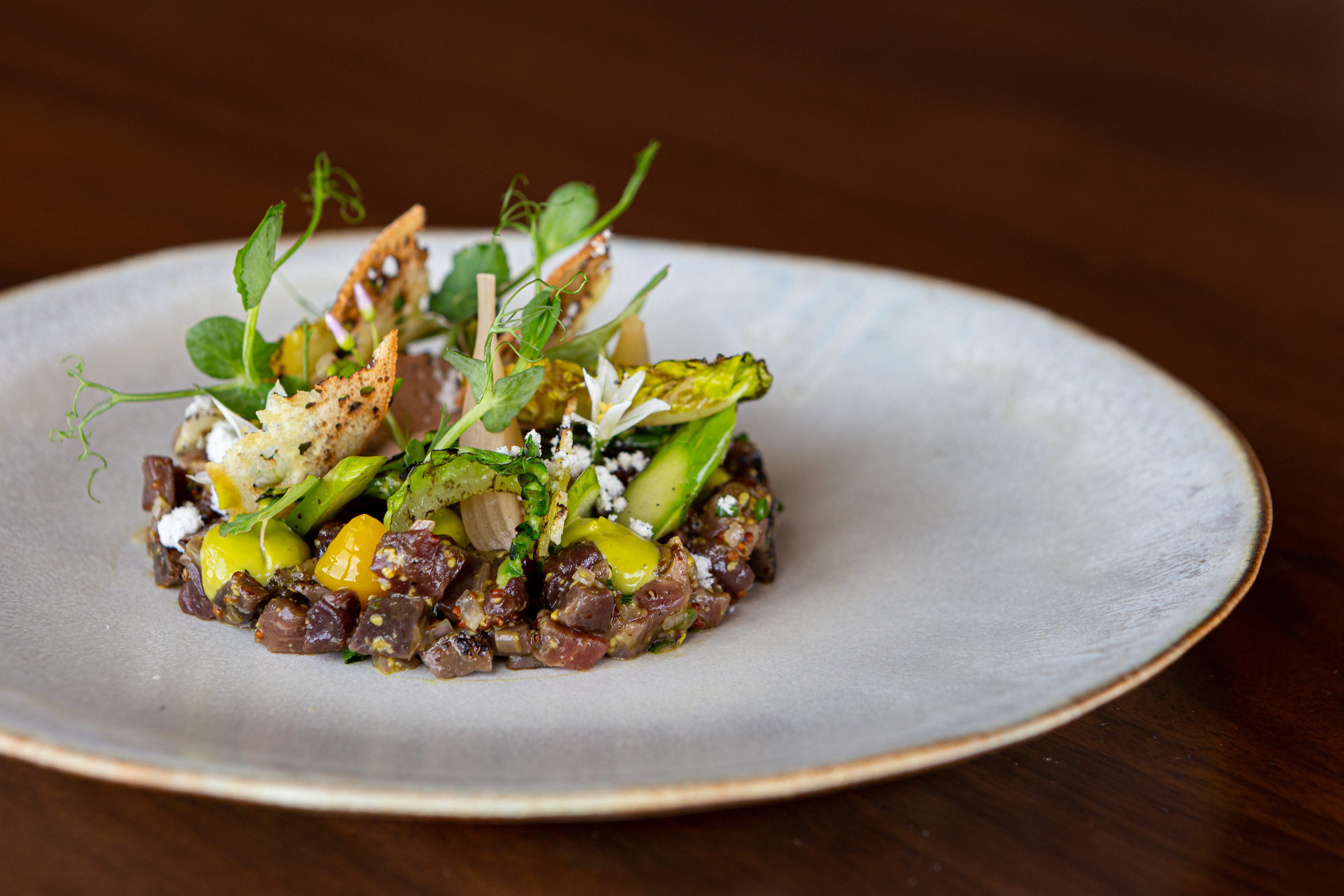 Bison tartare at Canoe, plated with crostini and greens